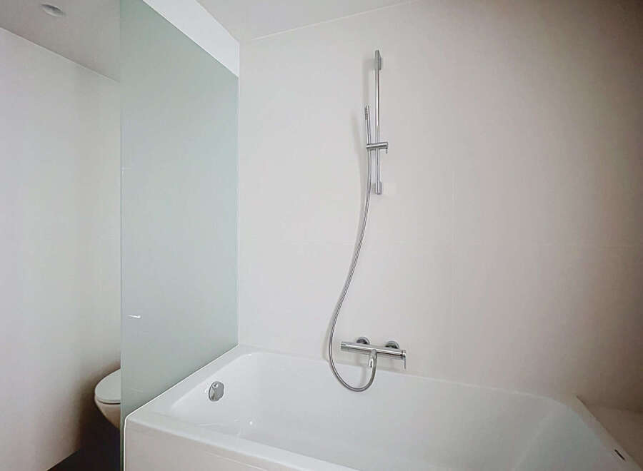This modern bathroom features a sleek white bathtub with a chrome showerhead and faucet, perfect for a relaxing soak.