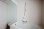 This modern bathroom features a sleek white bathtub with a chrome showerhead and faucet, perfect for a relaxing soak.