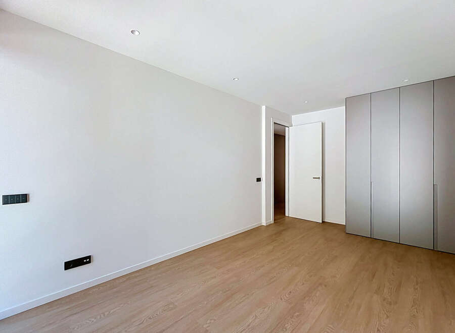 Experience modern living in this spacious, unfurnished room featuring sleek, built-in wardrobes and a clean, minimalist aesthetic.