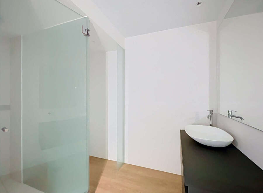 Experience modern luxury in this bathroom featuring a sleek glass shower enclosure and a minimalist vessel sink atop a dark vanity.