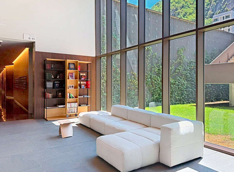 Experience modern living in this spacious apartment lobby, featuring a comfortable sectional sofa and a stylish bookshelf filled with literature.