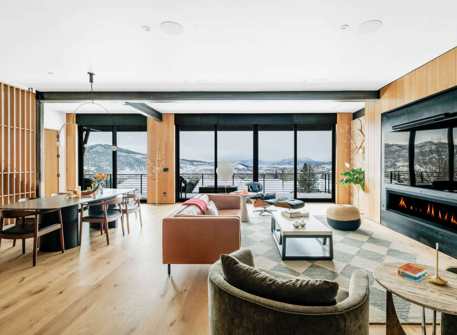 Experience luxury living with this stunning open-concept living and dining area, featuring a modern fireplace and expansive windows that showcase breathtaking mountain views.
