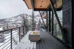 Experience luxury mountain living with this stunning contemporary home featuring a spacious deck overlooking a snow-covered landscape.