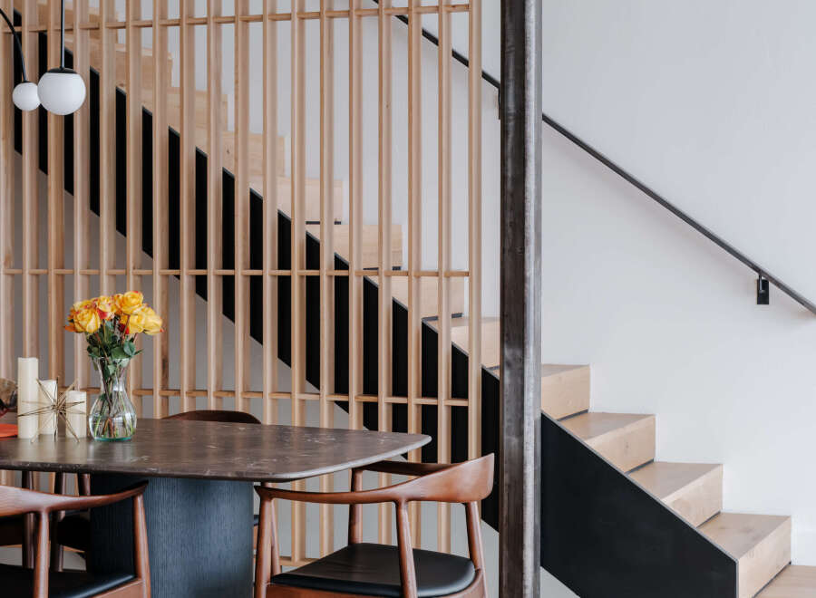 Experience modern living with this stunning dining area featuring a sleek, dark-toned table complemented by warm wooden chairs.