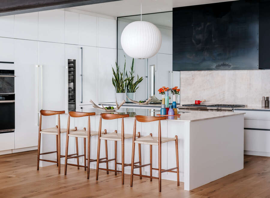 Experience modern luxury in this stunning kitchen, featuring sleek white cabinetry, a spacious island with bar seating, and high-end appliances.