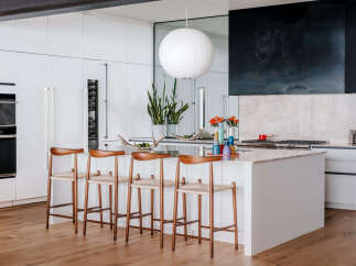 Experience modern luxury in this stunning kitchen, featuring sleek white cabinetry, a spacious island with bar seating, and high-end appliances.