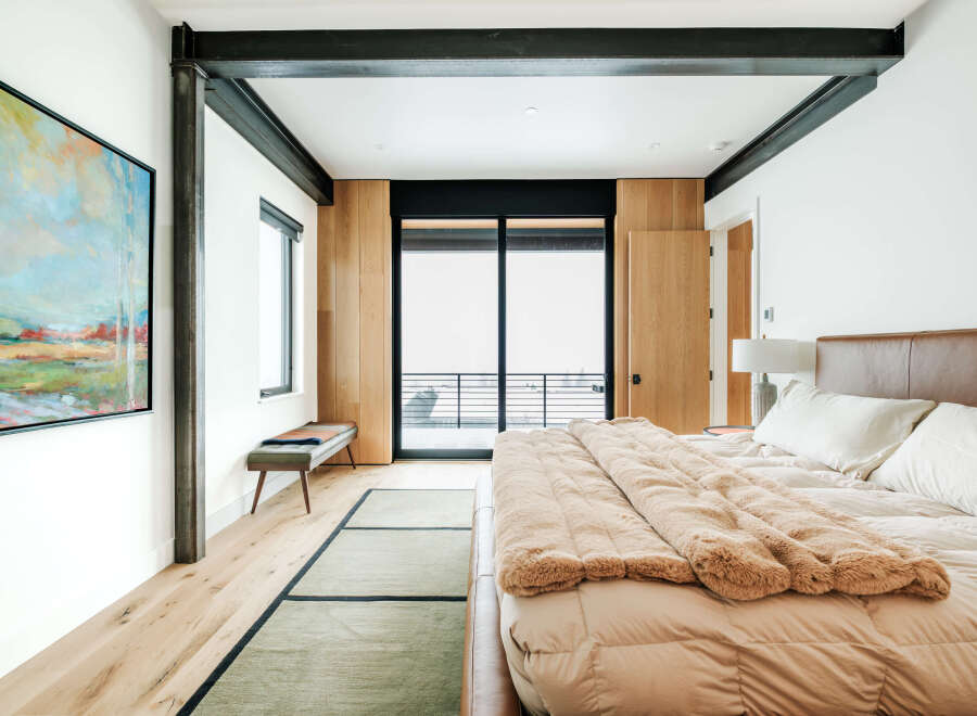 Experience modern luxury in this spacious bedroom featuring a plush king-sized bed with a rich leather headboard and a cozy faux fur throw.
