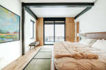 Experience modern luxury in this spacious bedroom featuring a plush king-sized bed with a rich leather headboard and a cozy faux fur throw.