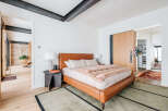Experience modern luxury in this master bedroom featuring a sleek, cognac leather bed and plush, faux fur throw.