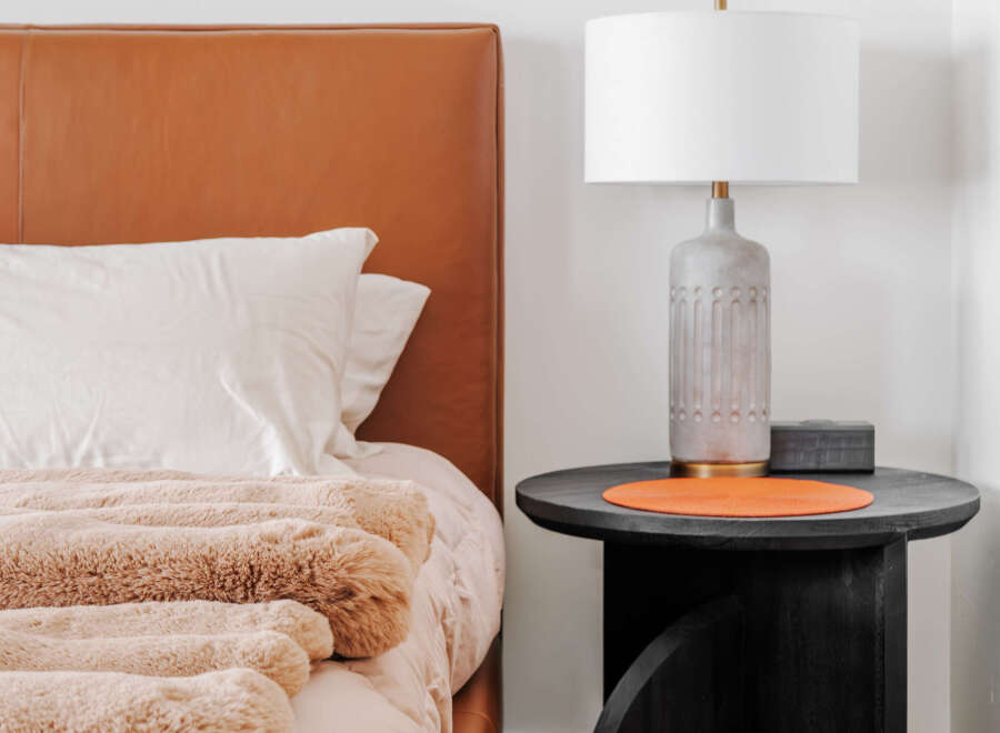 Experience modern comfort in this bedroom, featuring a luxurious tan leather headboard and plush, textured bedding.