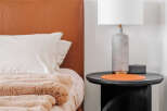 Experience modern comfort in this bedroom, featuring a luxurious tan leather headboard and plush, textured bedding.