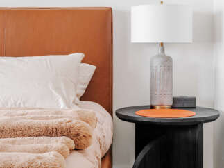 Experience modern comfort in this bedroom, featuring a luxurious tan leather headboard and plush, textured bedding.