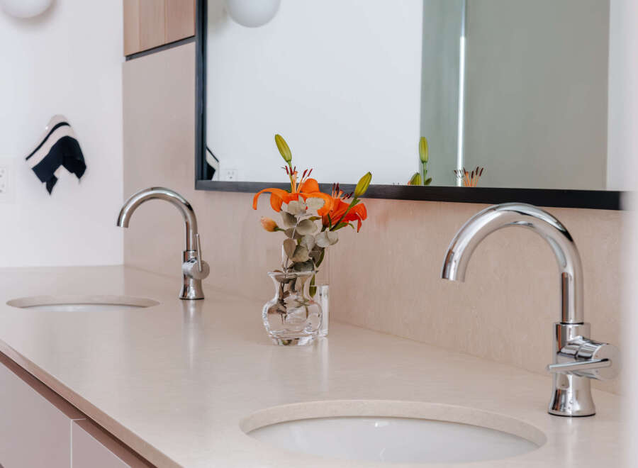 Experience modern luxury in this stunning bathroom featuring a dual vanity with sleek chrome faucets and integrated sinks.
