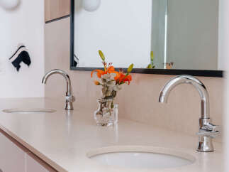 Experience modern luxury in this stunning bathroom featuring a dual vanity with sleek chrome faucets and integrated sinks.