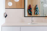 This modern bathroom features a sleek vanity with white drawers and a light-colored countertop, complemented by warm wood cabinetry above.