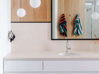 This modern bathroom features a sleek vanity with white drawers and a light-colored countertop, complemented by warm wood cabinetry above.