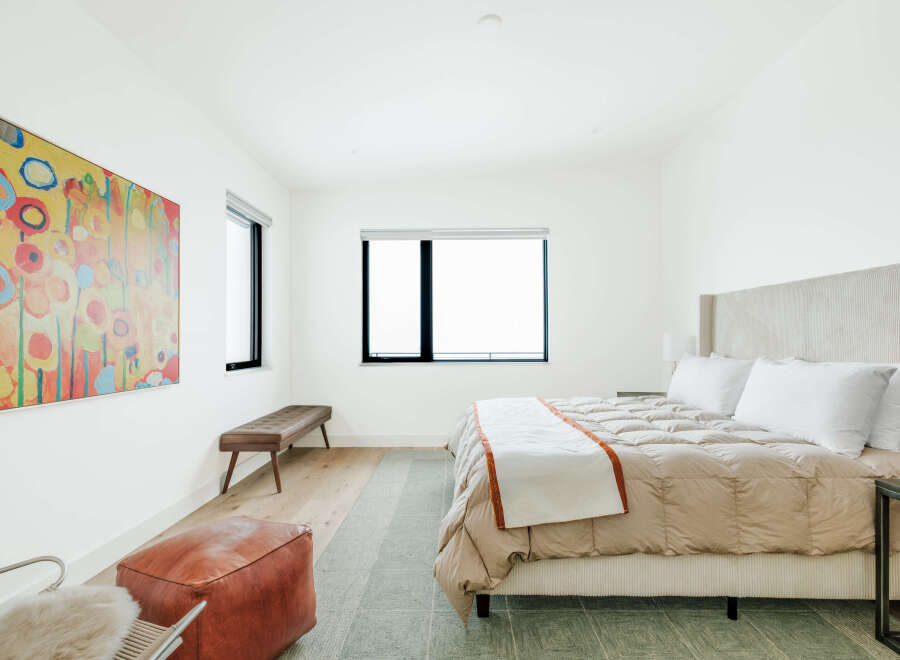 Experience modern comfort in this serene bedroom, featuring a plush king-sized bed with a textured headboard and a cozy duvet.