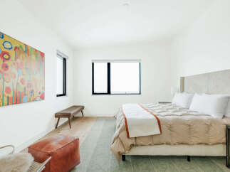 Experience modern comfort in this serene bedroom, featuring a plush king-sized bed with a textured headboard and a cozy duvet.