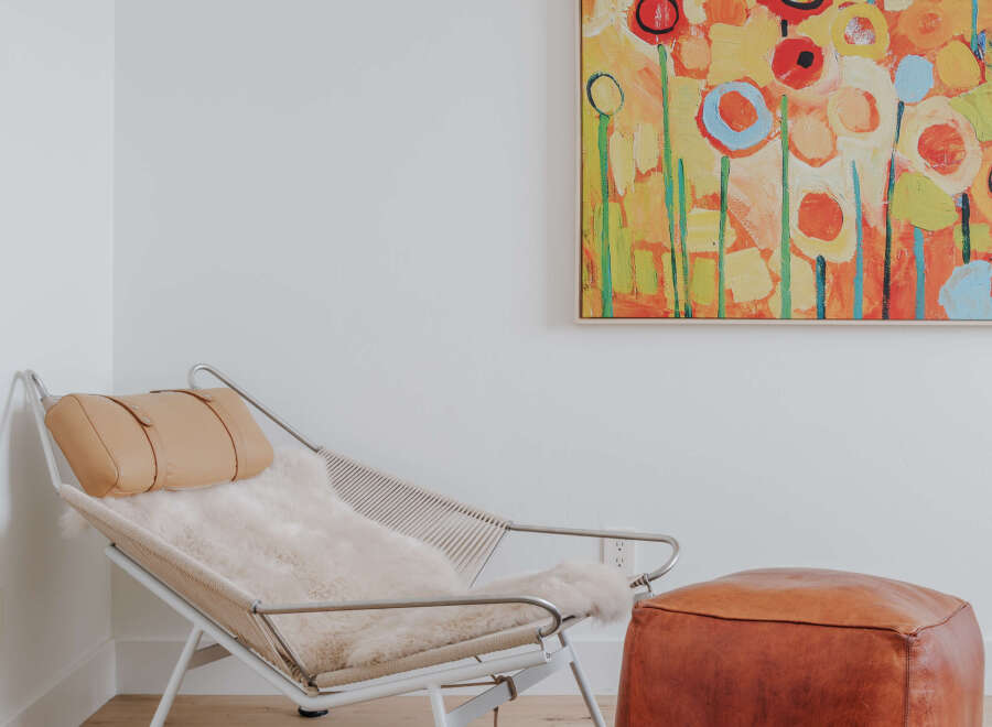 This inviting corner features a stylish lounge chair with a plush sheepskin throw and a complementary leather ottoman, perfect for creating a cozy reading nook.