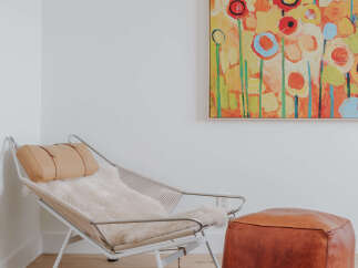 This inviting corner features a stylish lounge chair with a plush sheepskin throw and a complementary leather ottoman, perfect for creating a cozy reading nook.