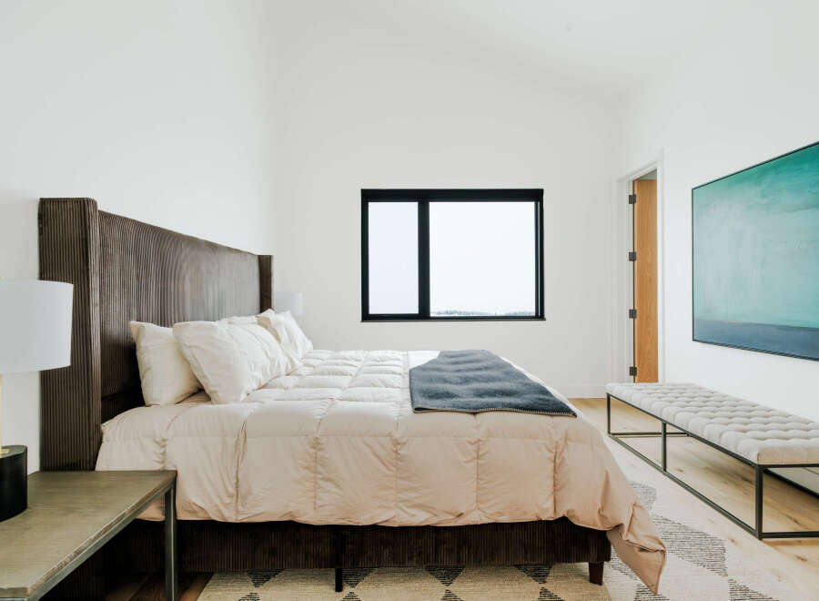 Experience modern comfort in this serene bedroom, featuring a plush king-sized bed with a striking corduroy headboard.