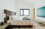 Experience modern comfort in this serene bedroom, featuring a plush king-sized bed with a striking corduroy headboard.