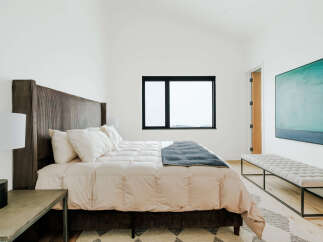 Experience modern comfort in this serene bedroom, featuring a plush king-sized bed with a striking corduroy headboard.