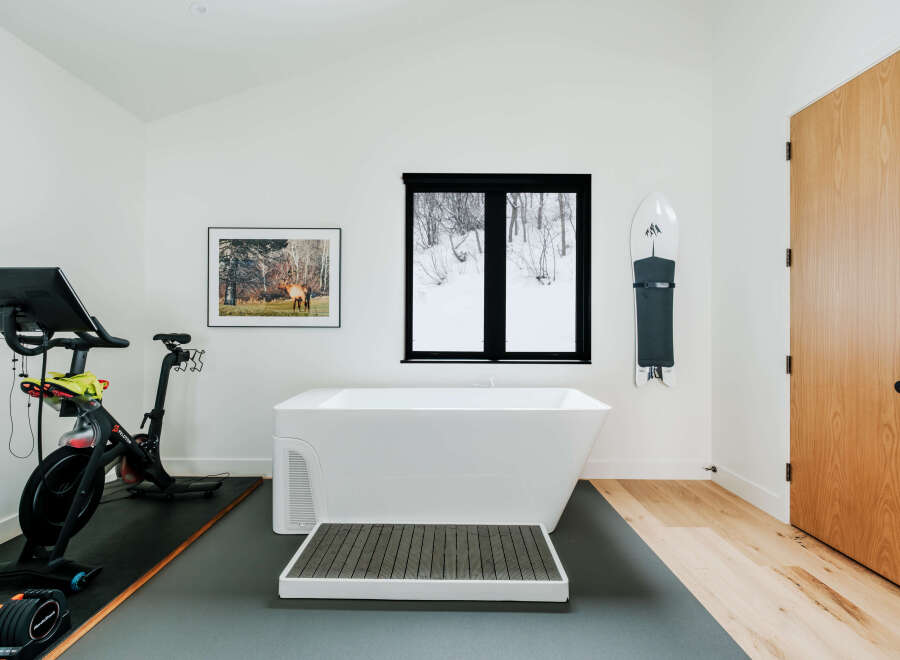 Experience ultimate relaxation and fitness in this unique spa-like bathroom, featuring a freestanding soaking tub and a Peloton bike for your wellness routine.