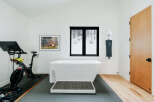 Experience ultimate relaxation and fitness in this unique spa-like bathroom, featuring a freestanding soaking tub and a Peloton bike for your wellness routine.