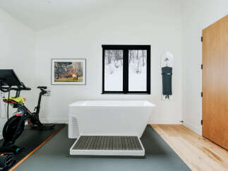 Experience ultimate relaxation and fitness in this unique spa-like bathroom, featuring a freestanding soaking tub and a Peloton bike for your wellness routine.
