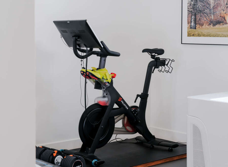 Elevate your fitness routine in this dedicated home gym space, featuring a top-of-the-line Peloton bike and adjustable dumbbells for a complete workout.