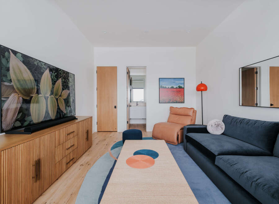 This modern living room features a large flat-screen TV mounted above a stylish wooden media console with ample storage.