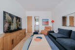 This modern living room features a large flat-screen TV mounted above a stylish wooden media console with ample storage.