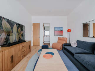 This modern living room features a large flat-screen TV mounted above a stylish wooden media console with ample storage.