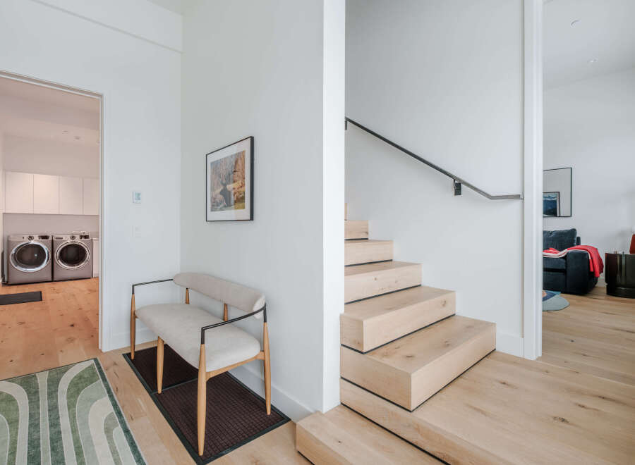 Step into this modern home featuring a sleek floating staircase with natural wood treads and a minimalist black handrail.