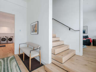 Step into this modern home featuring a sleek floating staircase with natural wood treads and a minimalist black handrail.