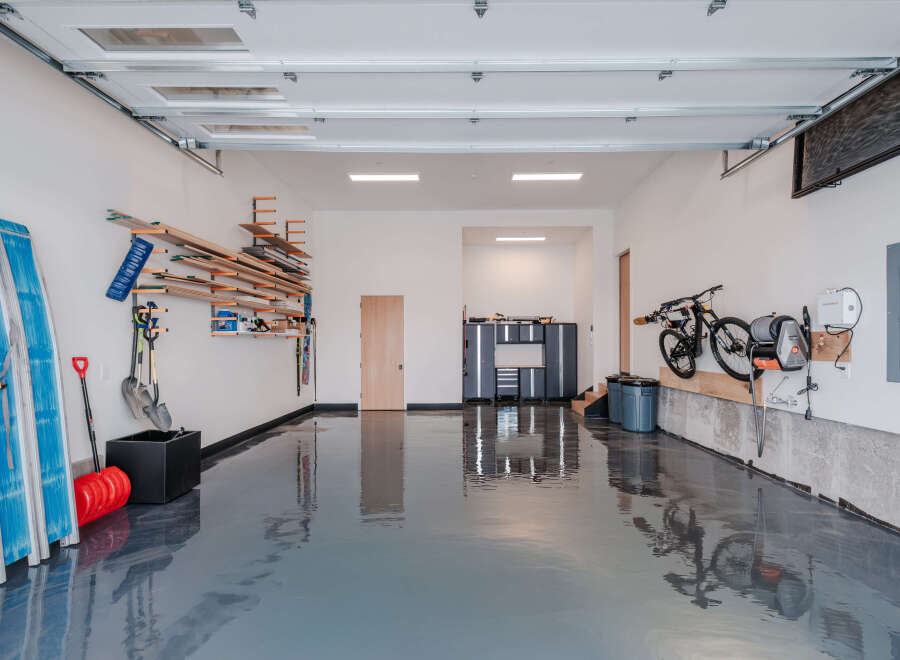 This spacious garage offers ample storage solutions, including wall-mounted shelving for lumber and tools, and a dedicated bike rack.