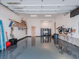 This spacious garage offers ample storage solutions, including wall-mounted shelving for lumber and tools, and a dedicated bike rack.