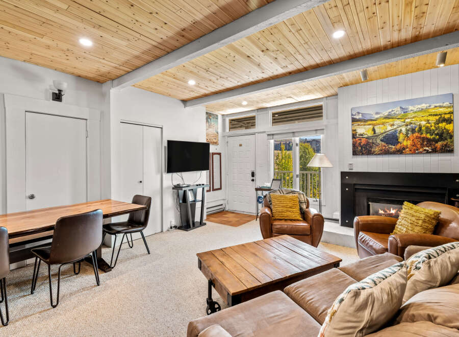 Experience cozy living in this charming mountain retreat, featuring a warm wood-paneled ceiling and a inviting fireplace.