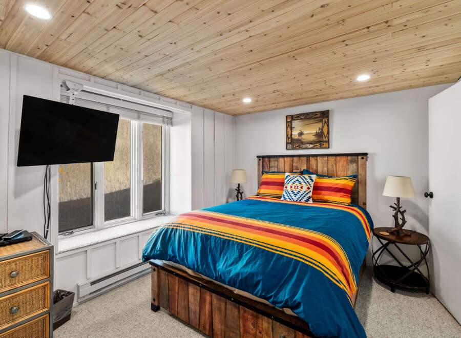 Experience rustic charm in this cozy bedroom featuring a vibrant Pendleton-style comforter and a unique reclaimed wood bed frame.