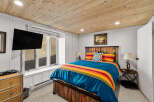 Experience rustic charm in this cozy bedroom featuring a vibrant Pendleton-style comforter and a unique reclaimed wood bed frame.