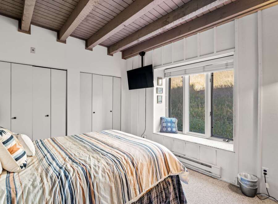 This cozy bedroom features a comfortable bed with striped linens, perfect for a relaxing getaway.