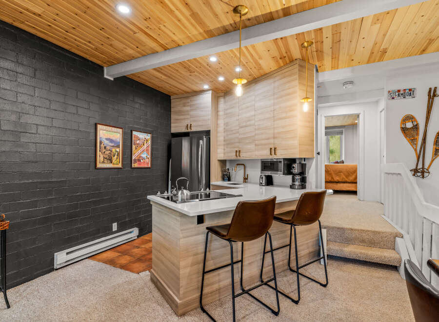 Experience modern mountain living in this stylish kitchen featuring a sleek island with bar seating and a chic backsplash.