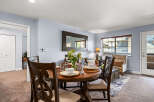Experience comfortable dining and living in this inviting space, featuring a round wooden dining table set for four and a cozy living area with plush seating.