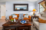 Step into this inviting living room, featuring a warm, caramel-colored leather sofa complemented by plush throw pillows and a cozy knit blanket.