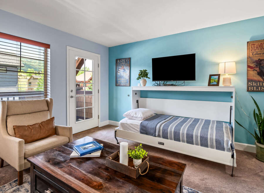 Experience mountain living in this charming room featuring a comfortable armchair and a convenient murphy bed.