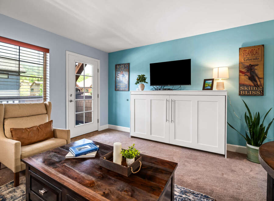 Experience mountain living in this cozy living room, featuring a comfortable armchair and a rustic wooden coffee table perfect for gathering.