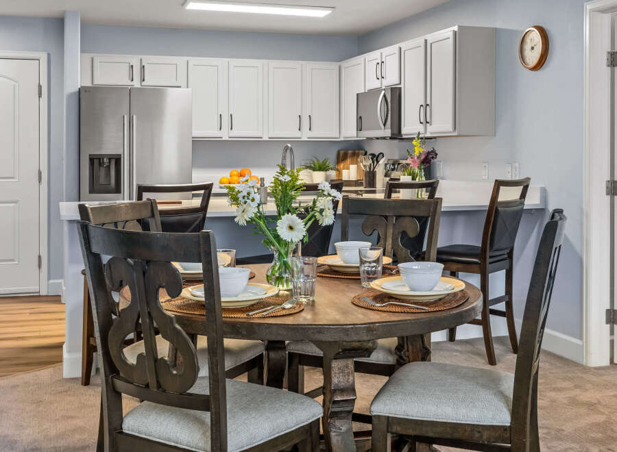 Enjoy meals in this charming dining area, featuring a rustic wooden table set for four and surrounded by elegant dark wood chairs.