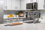 This modern kitchen boasts sleek white cabinetry and a spacious quartz countertop, perfect for meal preparation.