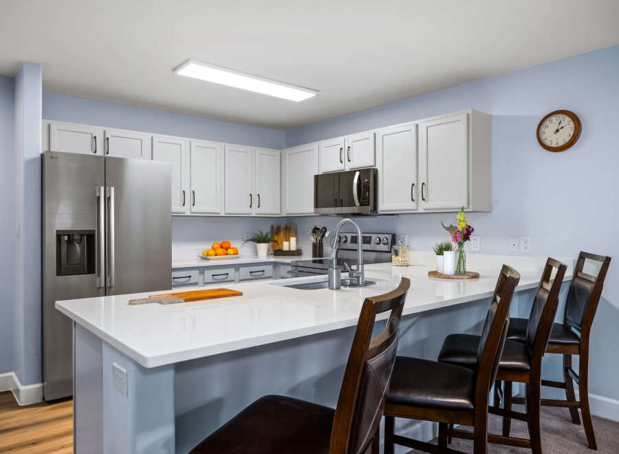 This modern kitchen features sleek white cabinetry and a spacious quartz island, perfect for meal prep and casual dining.